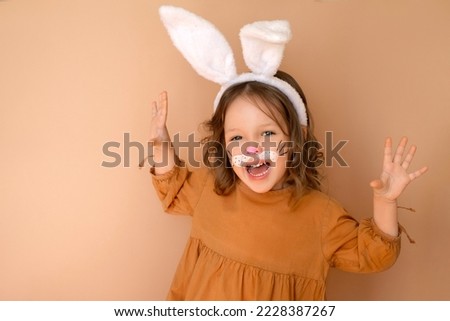A cheerful laughing girl with ears and face painted with water colors in image  of rabbit. bunny is symbol of Eastern calendar of 2023