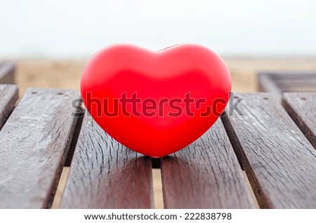 red hearts on the wood table in the beach symbolizing love, Valentine's Day, romantic couple. Calm ocean in the background.
