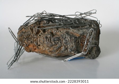 Large magnetite sample with paper clips attracted and covering the sample Royalty-Free Stock Photo #2228393011