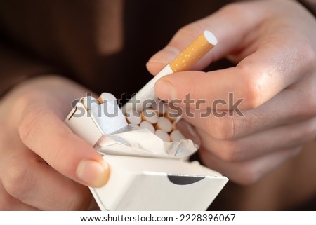 A man holds a pack of cigarettes in his hands, hand with a cigarette closeup. Person with a bad habit that is unhealthy Royalty-Free Stock Photo #2228396067