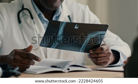 Unrecognizable man doctor african radiologist surgeon therapist osteopath show x-ray scan result MRI tomography roentgen of broken bones joints to patient with trauma surgery consultation in hospital