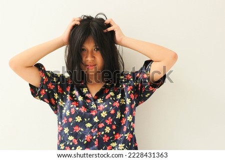 portrait of beautiful asian teenage girl child in satin nightgown with both hands holding head, messy hair, looking at camera. isolated