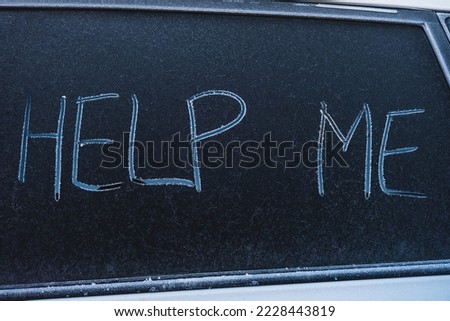 The text Help Me on the frozen glass of the car