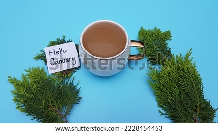 A cup of coffee, text hello January on a blue background.