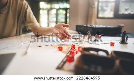 Role playing tabletop and board games hobby concept. Focus on dice d20. Blur background with hand and monster miniatures. Royalty-Free Stock Photo #2228464595