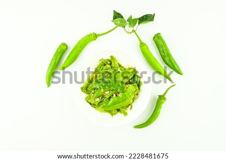 A plate of home cooked green peppers with garlic and tiger skin on a white background