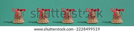 Festive natural décor Christmas idea with wooden bells and red ribbons on green background. Minimal New Year winter season concept.