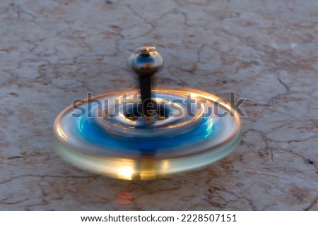 Small, blue and gold glass Hanukkah dreidel spinning in motion on  a stone wall.  Royalty-Free Stock Photo #2228507151