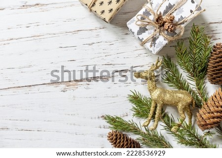 Christmas gold decor, christmas deer, fir tree twigs and gifts box on a white wood background. View from above. 