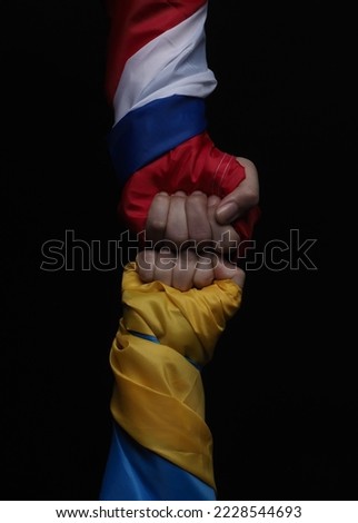 Russian flag and Ukrainian flag on a black background. Russian flag and Ukraine flag in hands showing symbol of struggle war political struggle political expressions Civil wars and territory conflict.