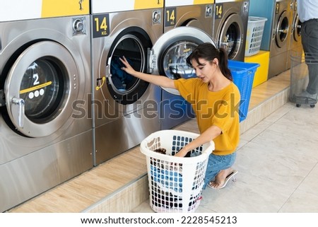 Asian people using qualified coin operated laundry machine in the public room to wash their cloths. Concept of a self service commercial laundry and drying machine in a public room. Royalty-Free Stock Photo #2228545213