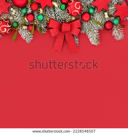Traditional Christmas festive fun red background border with tree decorations and winter fir mistletoe and snow. Composition for Xmas and New year holiday season.
