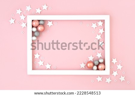 Christmas and New Year festive background on pastel pink with snowflakes and round bauble tree decorations with white frame. Minimal border design for the holiday season.