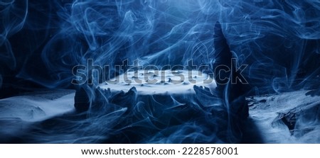 Mystical rocks in smoke on a dark background. Panoramic view of the abstract fog. Beautiful swirling blue smoke. Mockup for your logo. Wide angle horizontal wallpaper or web banner.