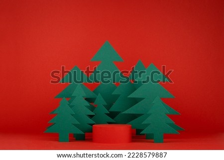 Christmas red cylinder podium mockup for presentation cosmetic products, gifts, goods with green paper spruce in minimal cartoon art style. New year template - pedestal for show, design.