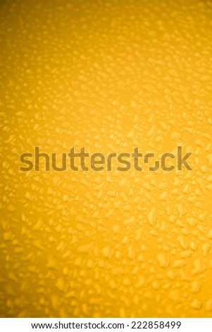 Rain droplets on yellow metal surface  