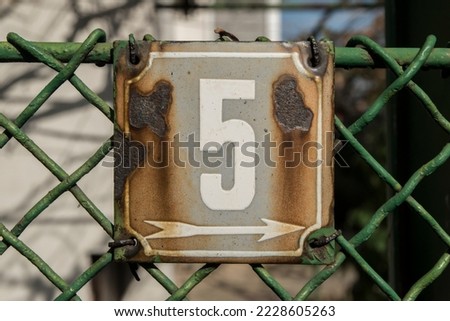 Weathered grunge square metal enameled plate of number of street address with number 5