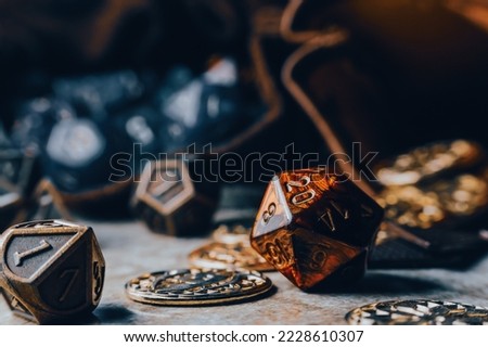 Close-up image of red role-playing gaming die on a gaming grid with game coins Royalty-Free Stock Photo #2228610307