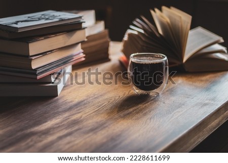 Stack of old books and coffee cup. Literature background. Open book and pile of books on the table. Coffee time in library. Retro books and espresso. Wisdom and knowledge.  Royalty-Free Stock Photo #2228611699