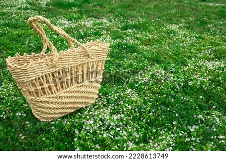 Wicker bag on green lawn with flowers. Concept image with copy space