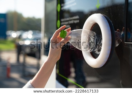 Woman uses a self service machine to receive used plastic bottles and cans on a city street Royalty-Free Stock Photo #2228617133