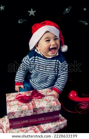 cute little boy opening christmas presents near red vintage telephone sitting on black background - studio shot