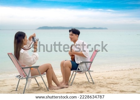 Asian traveller couple sitting and see sunset togather on the beach with longtail boat background at Phi phi island maya beach near Phuket, Thailand