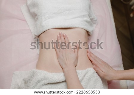  Close-up of a female masseur massaging a woman's abdomen in a spa. Top view. High quality photo