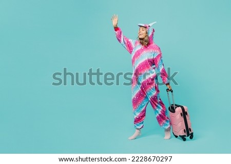 Full body traveler woman wear domestic costume with hoody hold valise isolated on plain pastel blue background. Tourist travel abroad in free spare time rest getaway. Air flight trip journey concept Royalty-Free Stock Photo #2228670297