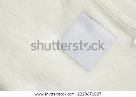 Blank white laundry care clothes label on fabric texture background