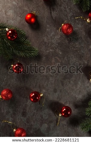 Red balls and Christmas tree branches on a dark background.