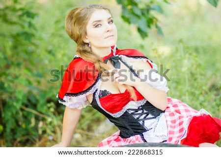 Portrait of a beautiful young woman in nature in the Little Red Riding Hood costume. Girl dressed as fairy-tale characters with beautiful make-up for Halloween