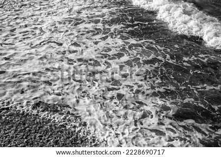 Ocean Shore with Foam and Waves Breaking in Black and White.
