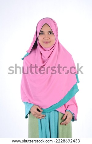 Portrait of 30s beautiful Muslim girl wearing hijab traditional religious cloth use hand touch her chin and looking to camera with a lovely smile on white background.