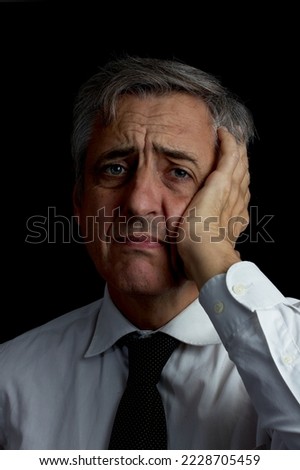 headache. concern. concentration. portrait. dark key. Man with gray hair, tie and white shirt.