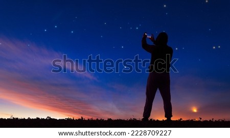 Photographing the night landscape on the phone. A man takes a picture of the starry sky on a smartphone.