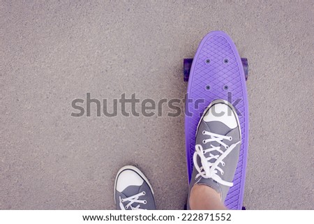Close up of a skateboard and sneaker