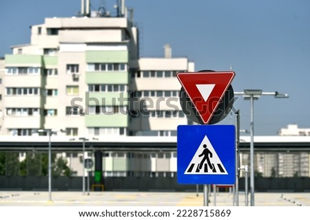 Parking for cars with a yield sign, crossing sign and pedestrian guidance nearby installed in a multi-storey car parking.