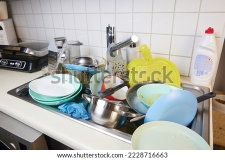 There is a lot of dirty dishes in the kitchen sink. Dirty dishes and unwashed kitchen appliances filled the kitchen sink. Royalty-Free Stock Photo #2228716663