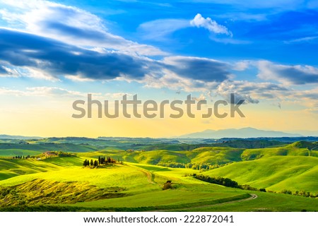 Tuscany, rural sunset landscape. Countryside farm, cypresses trees, green field, sun light and cloud. Volterra, Italy, Europe. Royalty-Free Stock Photo #222872041