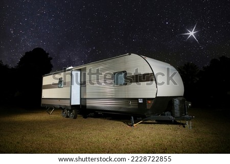 Camper trailer on a grassy spot with bright stars above