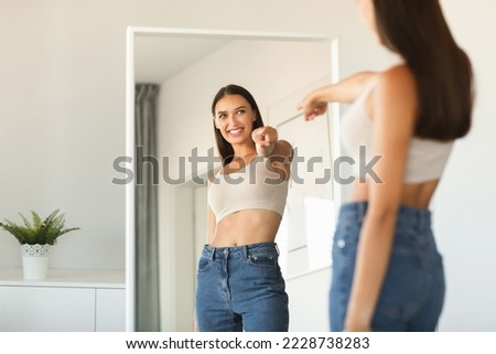 I choose myself. Playful young lady pointing finger at her reflection in mirror, enjoying successful slimming, free space. Self confidence concept Royalty-Free Stock Photo #2228738283