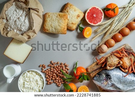 Allergy food concept. allergene - milk, fish, strawberry, bread, eggs, peanuts, citrus, wheat flower and others on grey backgrond                          Royalty-Free Stock Photo #2228741885