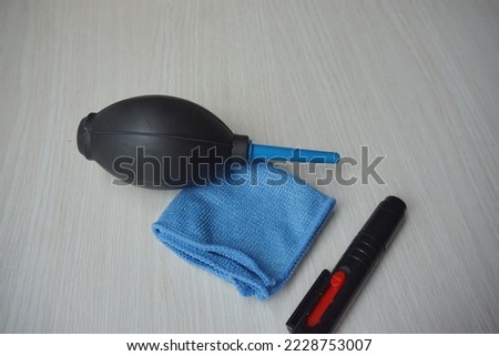 swabs, sensor cleaner, air blower, microfiber and lens pens stacked on a wooden textured white background. Cleaning set for photographic equipment maintenance. flat lay.