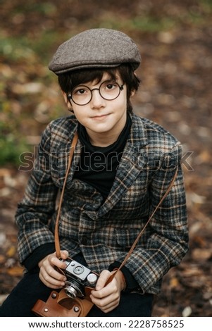 Boy with retro camera on blurred background in park