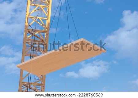 A complete laminated floor panel of a mass timber multi story green, sustainable, residential high rise apartment or office building construction project being lowered into place by a crane Royalty-Free Stock Photo #2228760569