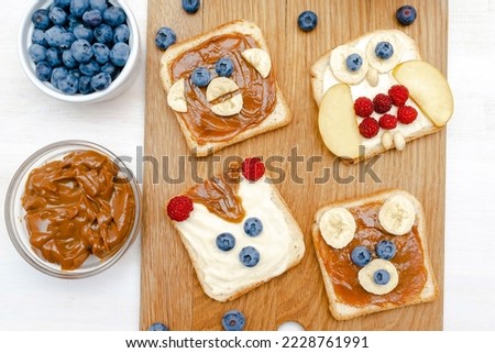 Funny cute bear,monkey,fox,owl faces sandwich toast bread with peanut butter,banana,blueberry,raspberry,milk. Kids childrens baby's sweet dessert healthy breakfast lunch food art,close up,top view