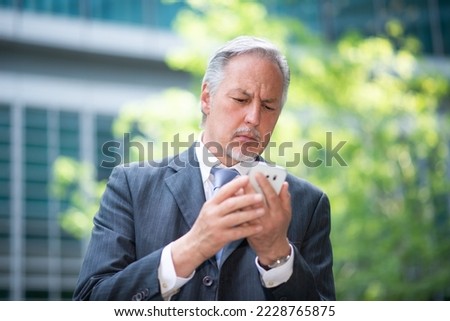 Senior business man using his smartphone outdoors