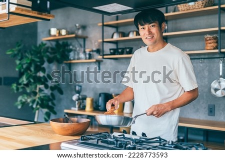 Asian man cooking in the kitchen Royalty-Free Stock Photo #2228773593