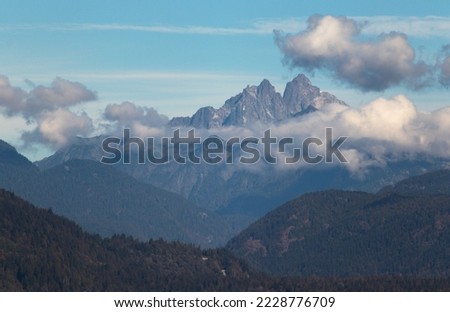 A rocky mountain shrouded in cloud with rolling hills in the foreground.  Mount Judge Howay located in British Columbia, Canada. Royalty-Free Stock Photo #2228776709